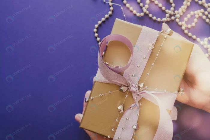 hands holding golden gift box with glitter pink r crcf8a64627 - title:تصویر استوک جعبه کادو طلایی با روبان صورتی و تزئینات - اورچین فایل - format:JPG - استوک - sku:crcf8a64627 - keywords: p_id:52776