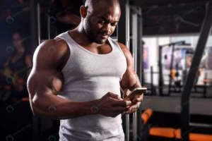 young male athlete uses phone during workout gym rnd143 frp22364222 - title:Home - اورچین فایل - format: - sku: - keywords: p_id:18